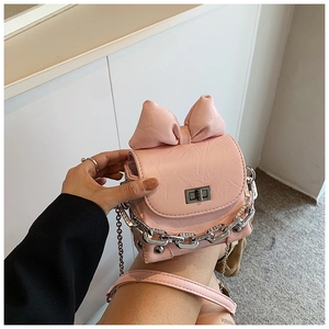 Detail view of pink mini bag with large bow decor, silver chain, and metal twist lock