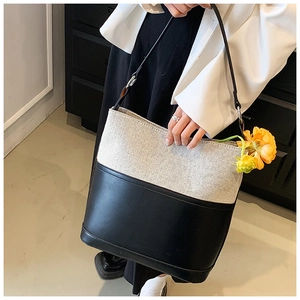Detail of minimalist bucket bag featuring contrast leather and textured grey fabric