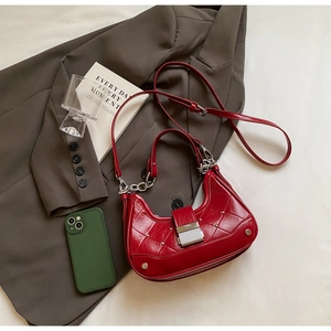 Detail of red quilted leather crescent bag with silver chain on a professional blazer