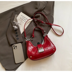 Red quilted crescent bag with studs and chain handle shown with office lifestyle props
