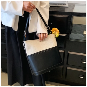 Detail of minimalist black and white tote bag with silver hardware and leather stitching