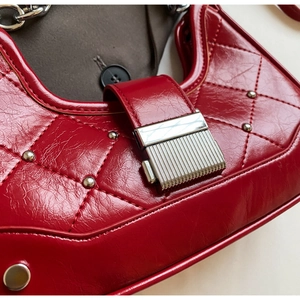 Close-up of red oil wax leather handbag with diamond stitching and silver rivets