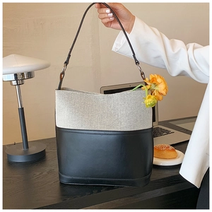 Close-up of minimalist bicolor canvas and black leather bucket bag on an elegant desk