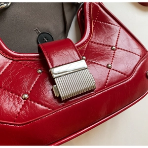 Close-up of bright red quilted baguette bag with silver hardware and rivet details