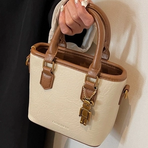 Mini sac cabas en cuir crème avec poignées marron et un élégant pendentif ours