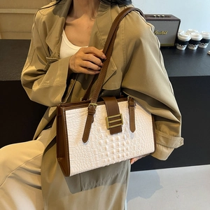 White crocodile pattern tote bag with brown leather trim and gold buckle shown on a model