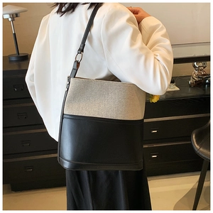 Detail of minimalist canvas and black leather bucket bag with silver metal ring hardware