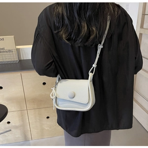 Detailed back side view of beige lychee grain saddle bag with pearl charm accessory