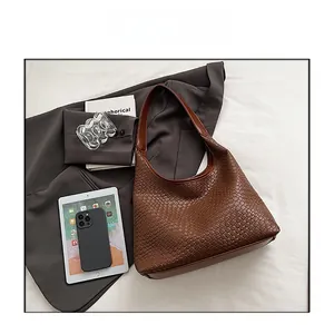 Detail view of woven brown hobo bag showing faux leather texture and smooth handle