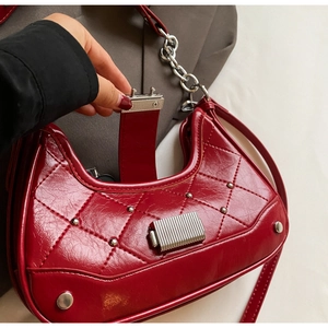 Close-up of a red quilted leather shoulder bag with silver studs and a metallic lock