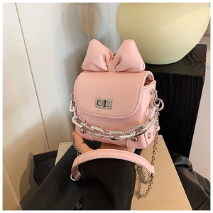 Macro detail of mini pink crossbody bag with large bow decor and silver buckle closure