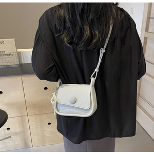 Close-up of gray lychee texture saddle bag featuring a pearl charm and round buckle