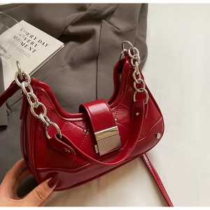 Macro shot of red quilted hobo bag with silver studs, chic chain and metal buckle
