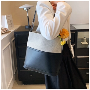 Detail view of contrast stitching bucket bag with black leather and cream canvas fabric