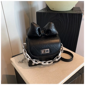 Macro detail of black crinkled leather texture and silver buckle on mini bow box bag