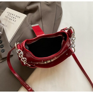 Detail view of glossy red patent leather baguette bag with silver studs and chain