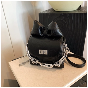 Detail of mini black bow bag with wrinkled leather texture and silver chain lock