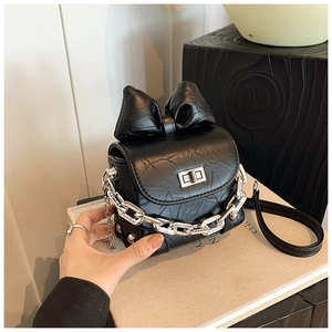Close-up of black mini box bag featuring ruffled faux leather and oversized bow detail