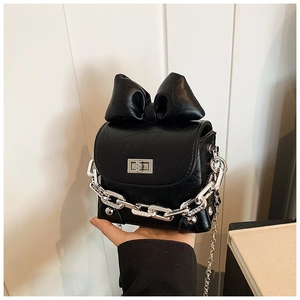 Detail view of mini black box bag with oversized bow and silver chain hardware