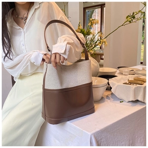 Detail of canvas and leather bucket bag featuring a minimalist contrast stitching texture