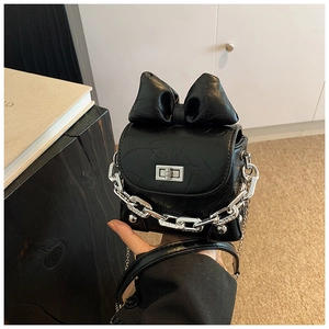 Detail of black mini box bag featuring a large bow and bold silver chain hardware