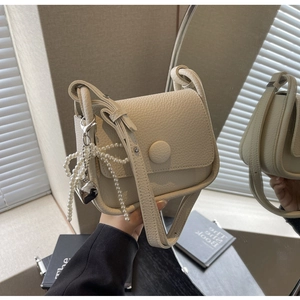Detail of off-white lychee pattern saddle bag featuring pearl bow and heart charm