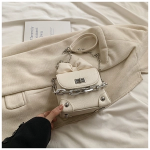 Detail of white pleated mini box bag featuring bow decoration and chunky chain detail