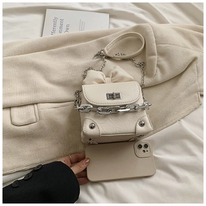 Detail of mini bow crossbody bag featuring silver chain and textured cream PU leather
