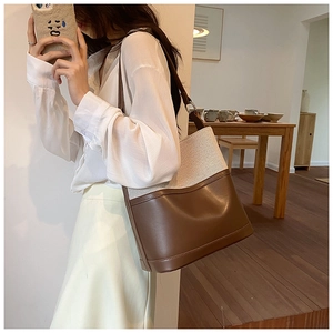Close-up of retro patchwork canvas and brown leather bucket bag on model shoulder
