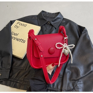 Detail of red lychee pattern saddle bag with large round buckle and pearl heart charm