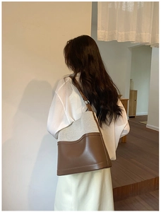 Detail view of the canvas and leather拼接 tote bag worn by a model in a cozy setting