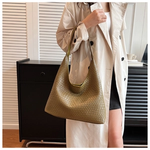 Detail view of woven leather olive green tote bag worn as a shoulder bag