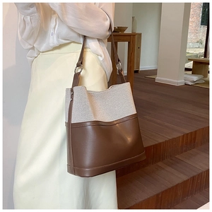 Detail of canvas and coffee leather bucket bag with metal buckle and shoulder strap
