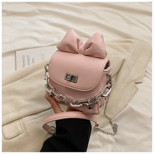 Detailed view of a pink mini box bag with oversized bow and silver chain on soft fabric