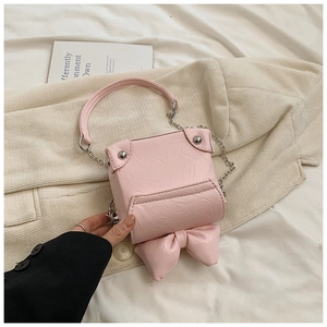 Detail of pink mini box bag featuring a large bow and textured faux leather finish