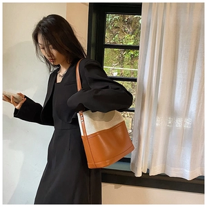 Detail of minimalist cream canvas and brown leather tote bag with metallic stud accents