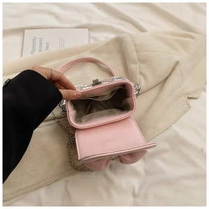 Detail view of pink mini bow bag interior with lining, side pocket, and silver chain strap