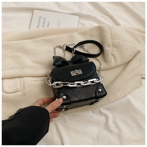 Detail of black leather crossbody bag featuring a silver chain and pleated texture bow