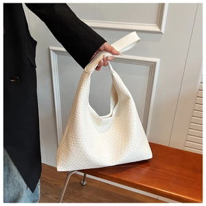 Detail of white woven texture on a large hobo bag held by a model in a stylish interior