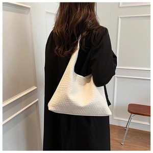 Detailed close-up of woven cream large tote bag texture on female model in coat