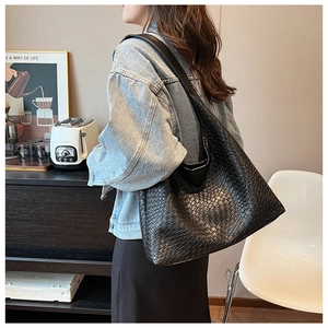Detail of a large black woven hobo bag showing texture and spacious design on a model
