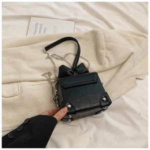 Close-up of black bow box bag with wrinkled PU leather texture and silver chain strap