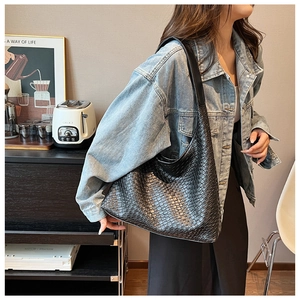 Detailed view of black woven hobo bag with checkered texture worn on a shoulder