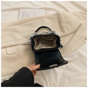 Detail of black PU leather handbag with beige fabric lining and thick silver metal chain