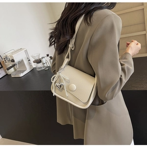 Chic beige lychee pattern saddle bag with pearl heart pendant shown on shoulder