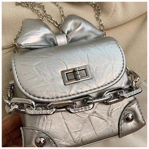 Detail of silver mini box bag featuring a large bow and decorative chunky chain strap
