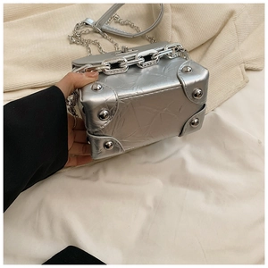 Detail of silver pleated mini box bag featuring metallic studs and a chain handle