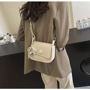 Close-up of cream lychee texture saddle bag with elegant pearl heart charm detail