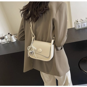 Creamy lychee grain saddle bag featuring pearl bow charm and silver heart pendant