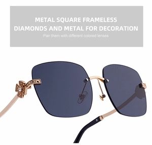 Close-up of frameless sunglasses with gold metal temples and diamond clover detailing